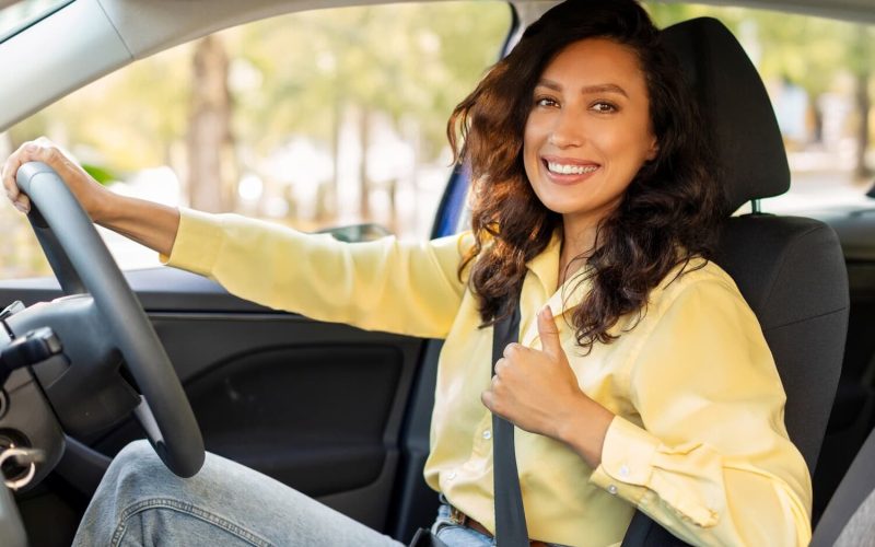 happy-european-woman-showing-thumb-up-smiling-sitting-inside-new-modern-car-first-road-trip-1-e1743712420922.jpg